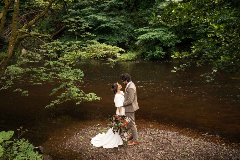 a bride and groom on the riverbank at Brinkburn Northumberland